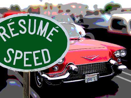 a resume speed sign in front of a classic cadillac